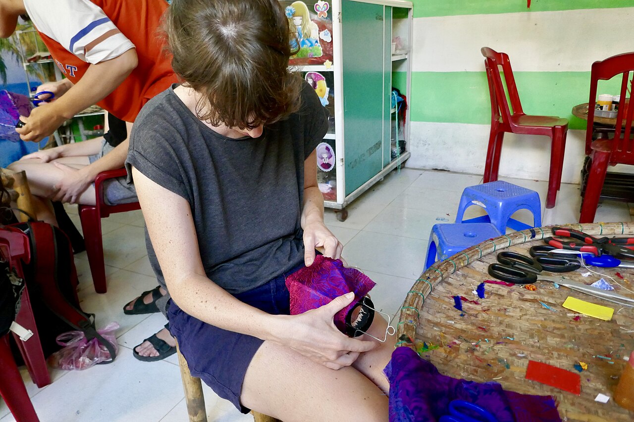Thao tác bọc vải lên khung đèn lồng tại Hội An minh họa việc kiểm tra đường căng và mép hoàn thiện