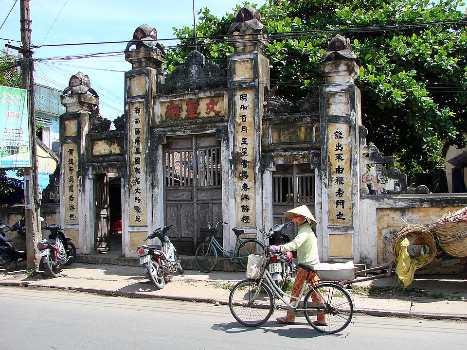 Người đi xe đạp qua một công trình trên đường phố Hội An minh họa cách gom điểm theo cụm