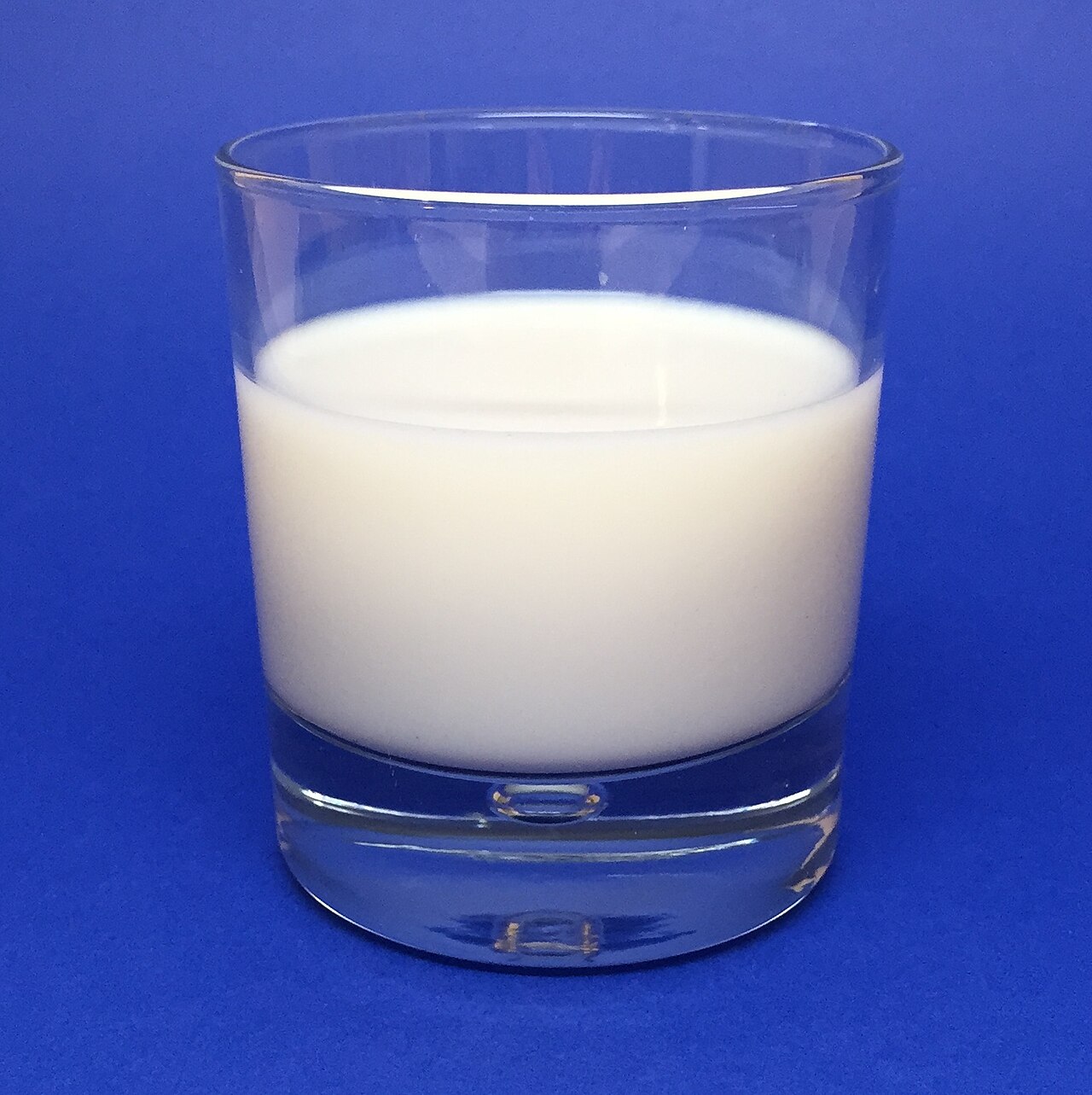 Ly sữa trắng trên nền xanh minh họa việc chọn sản phẩm sữa