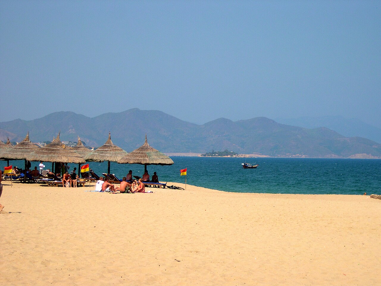 Bãi biển Nha Trang có cờ cảnh báo và khu nghỉ dưới ô minh họa kế hoạch đi Nha Trang cùng trẻ nhỏ